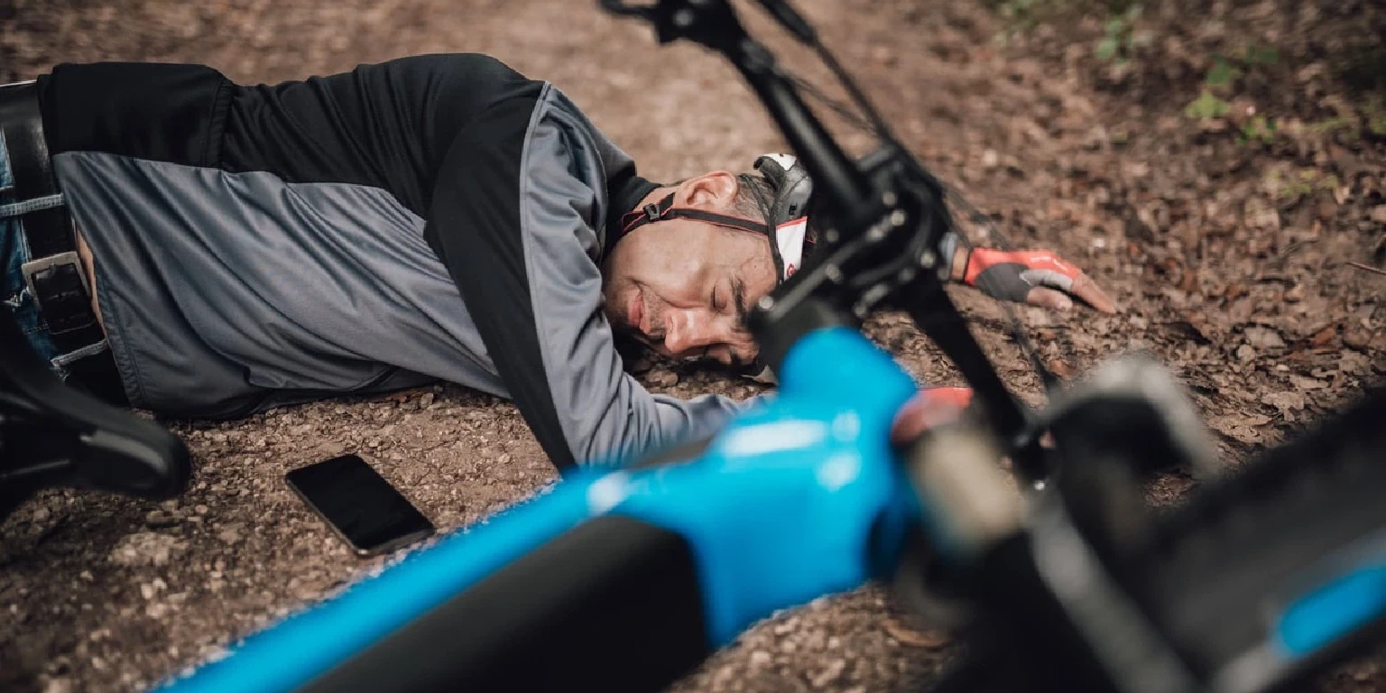 Mann liegt nach einem Sturz mit seinem E-Bike auf dem Waldboden